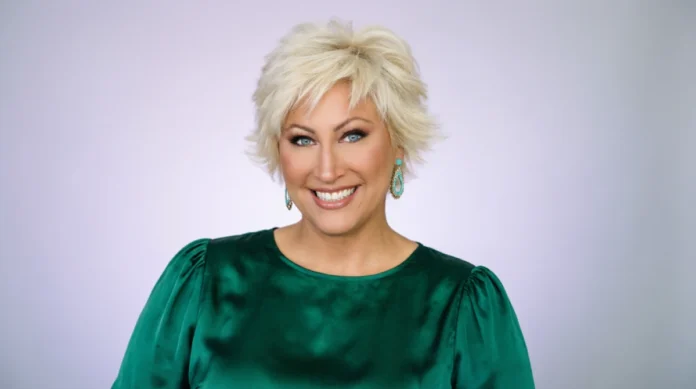 Kim Gravel Net Worth: The Real Numbers Behind a $1 Billion QVC Brand Smiling Kim Gravel with short blonde hair wearing emerald green dress with puffy sleeves and turquoise earrings